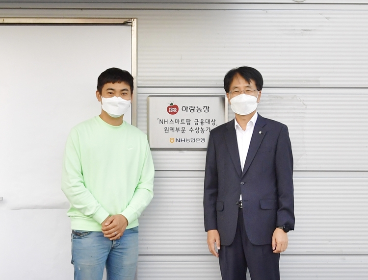 손병환 농협은행장(오른쪽)과 허정수 하랑농장 대표(왼쪽)가 12일 전북 김제시에 위치한 ‘하랑농장’에서 ‘NH 스마트팜 금융대상’ 현판식을 진행한 후 기념 촬영을 했다(사진: NH농협은행).
