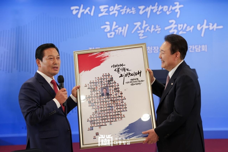 조재구 회장이 전국 228명 시장·군수·구청장들의 얼굴이 담긴 대한민국 지도 모양 그린 액자를 윤 대통령에게 전달하고 있다. (사진_대통령실 제공)