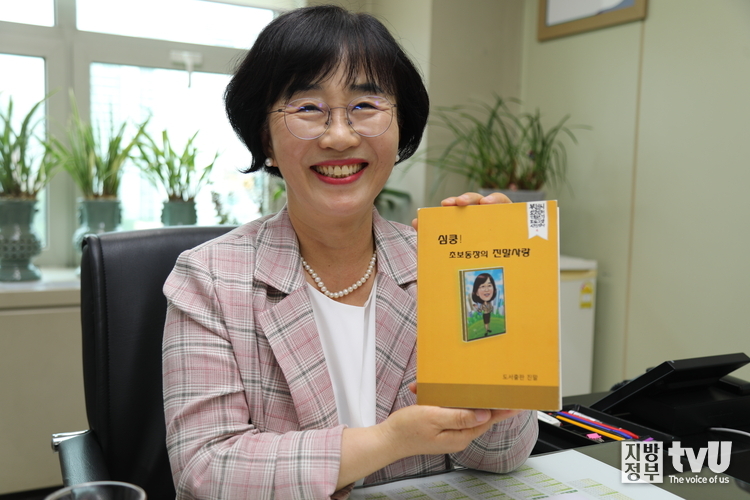 안윤경 국장이 자신이 펴낸 책 '심쿵! 초보동장의 진말사랑'을 들고 활짝 웃고 있다 